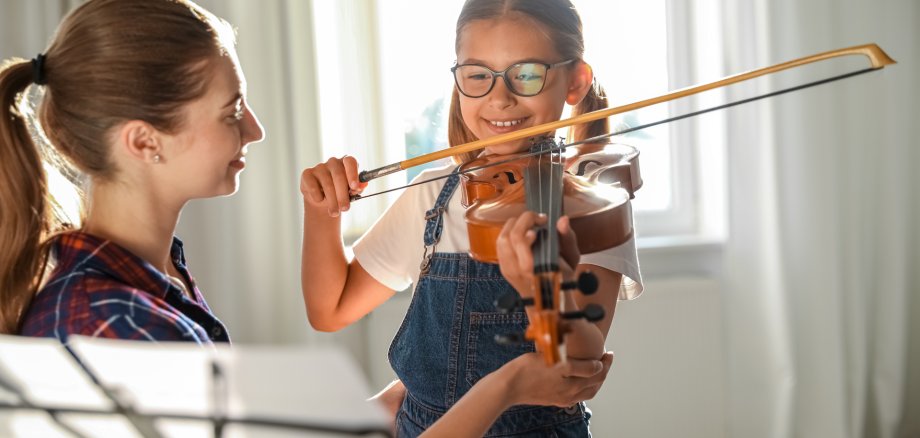 Young,Woman,Teaching,Little,Girl,To,Play,Violin,Indoors Young,Woman,Teaching,Little,Girl,To,Play,Violin,Indoors