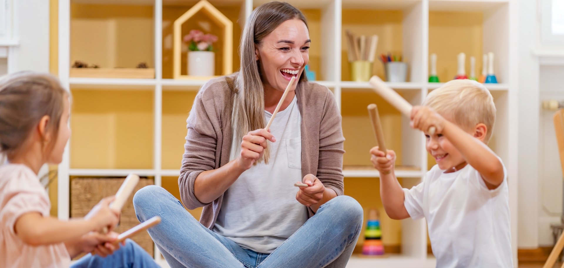 Kindergarten,Teacher,With,Children,Sitting,On,The,Floor,Having,Music