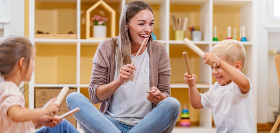 Kindergarten,Teacher,With,Children,Sitting,On,The,Floor,Having,Music